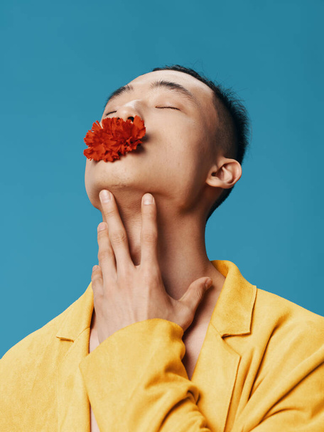 Uma máquina social com uma flor vermelha na boca inclinou a cabeça para trás aparência asiática - Foto, Imagem