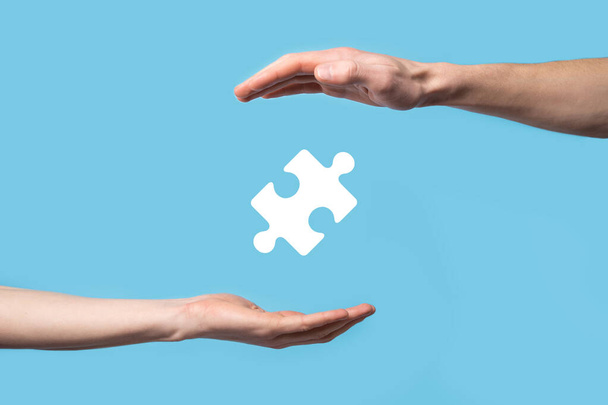 Férfi kéz kezében puzzle ikon kék háttér. két társaság vagy közös vállalkozás, partnerség, egyesülés és akvizíciós koncepció egyesülését képviselő darabok - Fotó, kép