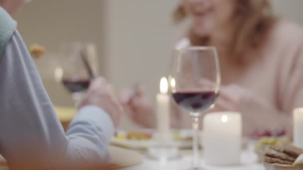 Midsection tiro desfocado de casal familiar comer refeição e falar enquanto tendo jantar romântico à mesa com vinho e velas - Filmagem, Vídeo