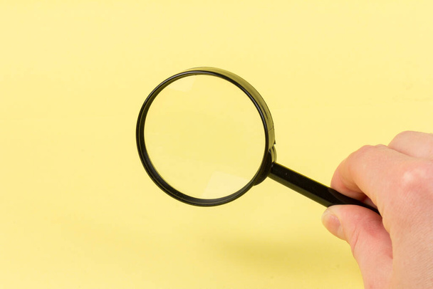 Close up of a magnifying glass on a yellow background. Science research concept. Top view. Flat lay. Copy space. Creative minimalism. Design element. - Photo, Image