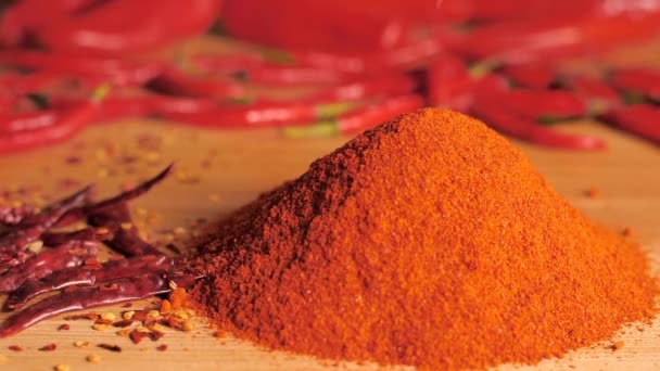 Whole red chilies dropping on a heap of chili powder - tropical hot spices. Closeup shot of dry roasted red pepper and its lal mirchi powder on a wooden table - Indian seasoning Masala - Footage, Video
