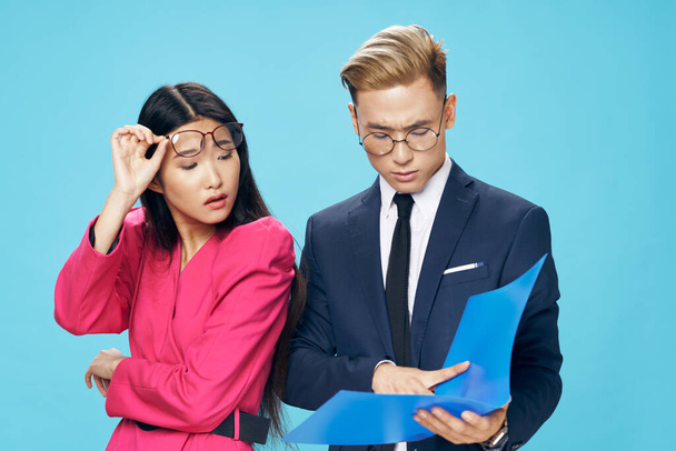 business man in a suit and a woman in a pink jacket with documents in hands on a blue background - Foto, immagini