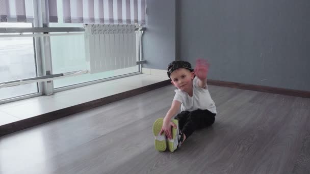 Kleiner Junge macht Dehnübungen und macht Spagat nach Breakdance-Hip-Hop-Tanzstunde - Filmmaterial, Video