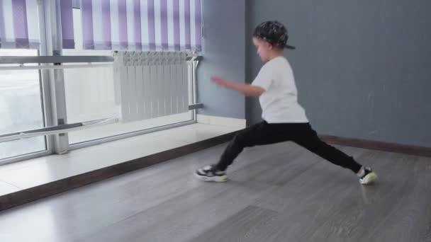 Petit garçon fait de l'exercice pour étirer et fait les fentes après la leçon de danse hip-hop breakdance - Séquence, vidéo