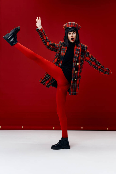 emotionale Frau mit erhobenem Bein helle Kleidung roter Hintergrund - Foto, Bild
