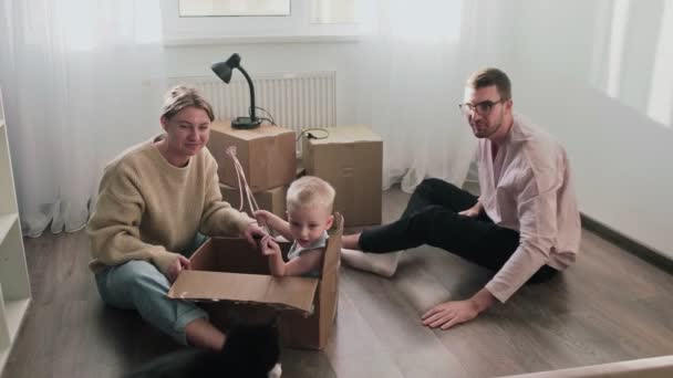 Happy couple relaxes after moving in a new home. Couple sits on floor and plays with their child - Footage, Video
