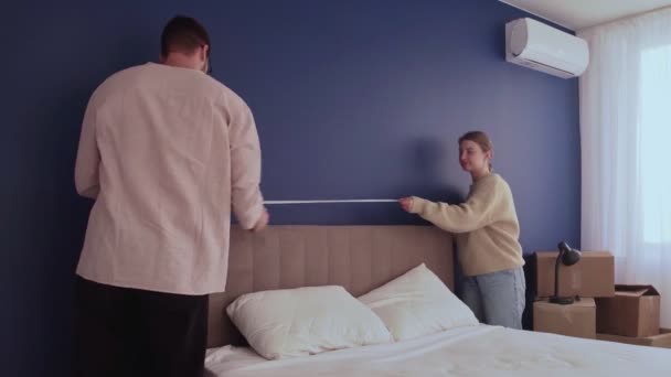 Young couple prepare to moving out relocation. Man and woman uses a tape measure to measure the bed - Footage, Video