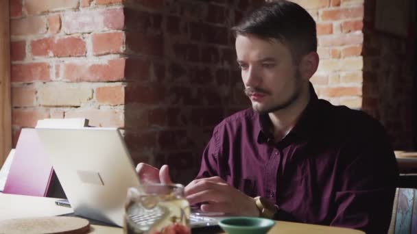 Porträt eines attraktiven jungen Mannes, der im Café an seinem Laptop arbeitet - Filmmaterial, Video