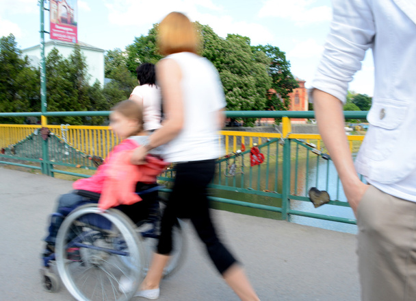 Behindertes Kind im Rollstuhl begleitet Mutter - Foto, Bild