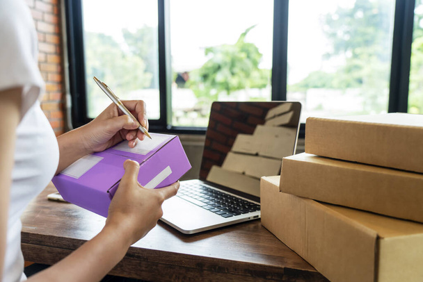 Briefzustellerin Verkäuferin bereitet den Briefkasten vor. Schreiben Adressat auf Packing.Cardboard Parcel Box für den Online-Verkauf. E-Commerce Startup Small Business Owner Shipping Products Concept. über Kopf  - Foto, Bild