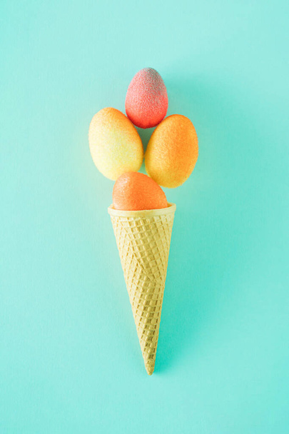 cone de sorvete cheio de ovos coloridos em um fundo azul. - Foto, Imagem