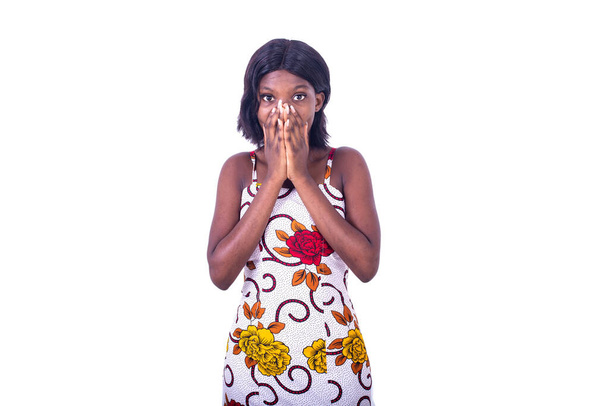 ένα κορίτσι φορώντας loincloth φόρεμα στέκεται σε λευκό φόντο που καλύπτει το στόμα με τα χέρια που αναζητούν έκπληκτος - Φωτογραφία, εικόνα