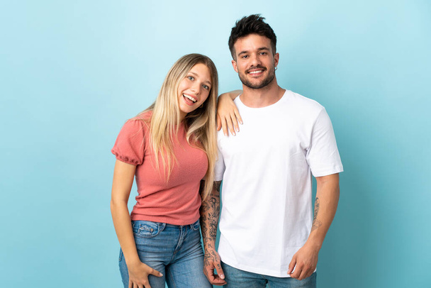 Young caucasian couple isolated on blue background happy and laughing - Photo, Image