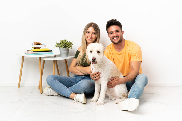 Young caucasian couple with dog staying at home keeping the arms crossed - Photo, Image