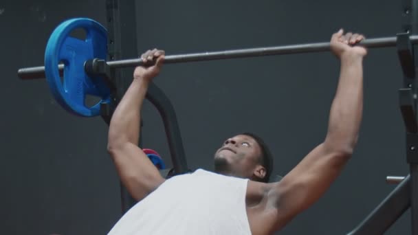 młody muskularny afro człowiek ćwiczenia ławka wyciskanie klatki piersiowej na ławce ze sztangą - Materiał filmowy, wideo