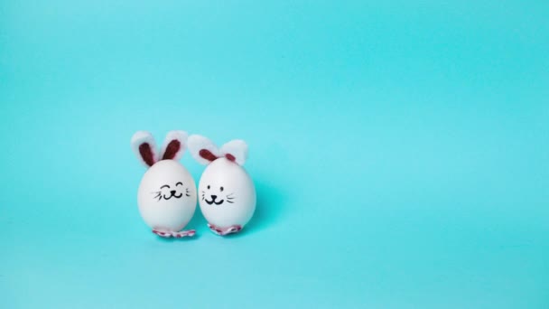 4k Two cute Easter bunnies made of white chicken eggs move and congratulate on holiday. Happy Easter Bunny Day Concept. Light blue background. Holiday greeting card. Stop motion animation. Copy space. - Footage, Video
