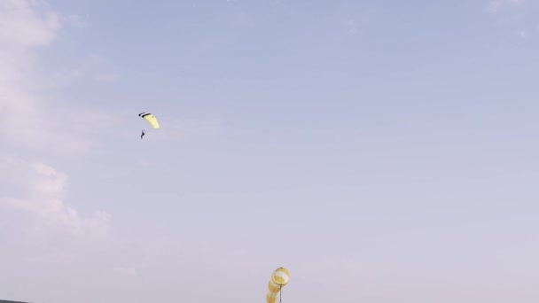Paracaidista aterrizando en un pequeño aeródromo después de un maravilloso viaje aéreo. Paracaídas amarillo. Paracaidista profesional. Clases de vuelo en paracaídas - Imágenes, Vídeo