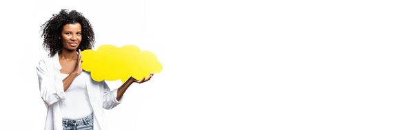 Donna afroamericana con bolla di discorso gialla sorridente alla macchina fotografica isolata su bianco, striscione  - Foto, immagini