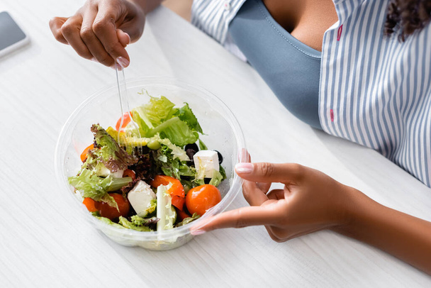 Cropped view of african american woman holding fork near salad  - Photo, Image