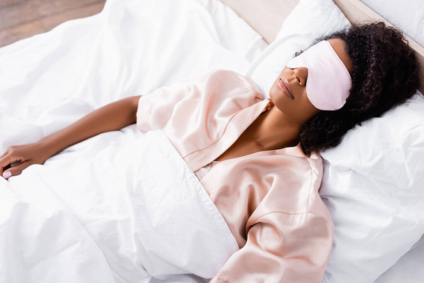 African american woman in mask sleeping on bed  - Photo, Image