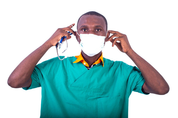 jovem médico masculino de uniforme usando máscara médica e olhando para a câmera. - Foto, Imagem