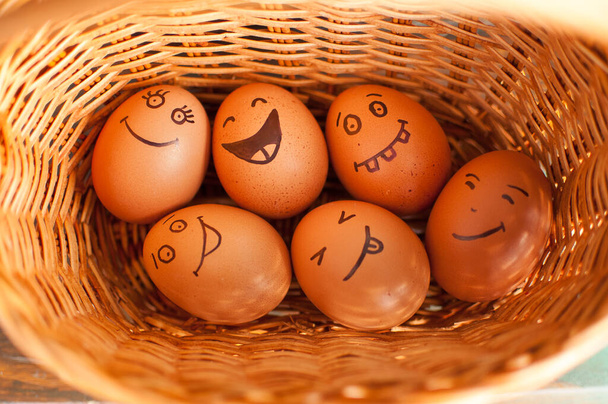 Hromada vajec s ručně kreslenými tvářemi na slaměném koši, velikonoční příprava, pojetí sváteční nálady - Fotografie, Obrázek