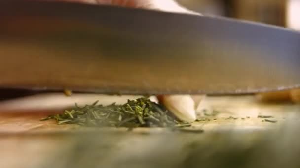 Vrouwelijke handen hakken verse bladeren uit een takje rozemarijn op een houten snijplank. Proces van het koken van perfecte oven geroosterde aardappelen. Tijdsverloop - Video