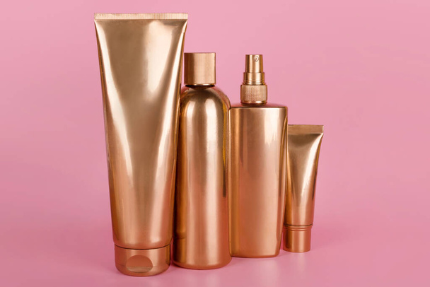 ゴールデンボトル、ピンクの背景に化粧品。ラグジュアリーな美容スタイル。金の化粧品容器。モックアップボトル、化粧品ブランド、髪やボディケアの概念。コピースペース,空のテキストの場所 - 写真・画像