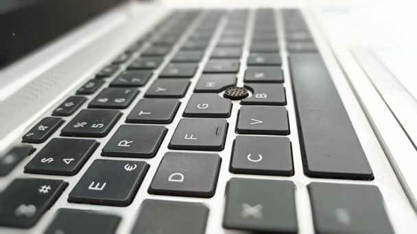 Szczegóły klawiatury laptopa QWERTY. Komputer jest srebrny i ma czarne klawisze z białymi literami i cyframi. - Zdjęcie, obraz