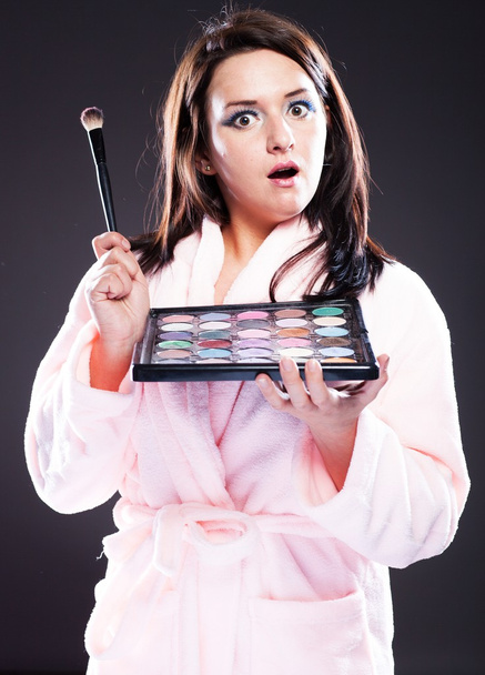 Surprised woman in bathrobe and make up palette - 写真・画像