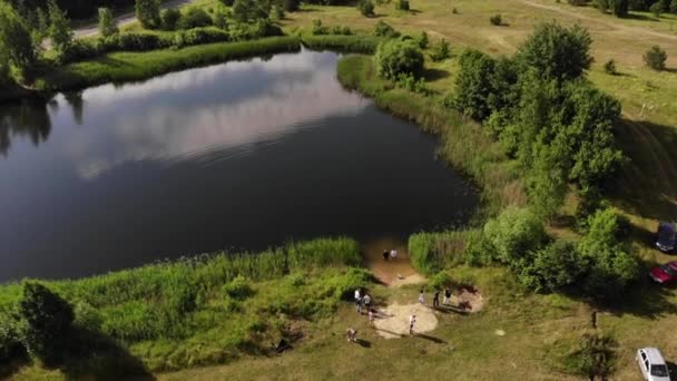Top view of two pastors standing in the lake during a baptism in the name of Christ and a group of people on the shore - Footage, Video