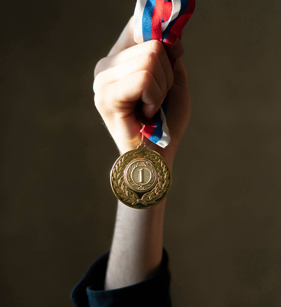 το χέρι ενός campion κρατώντας ένα χρυσό μετάλλιο, απλή νικητής τυχερή έννοια - Φωτογραφία, εικόνα