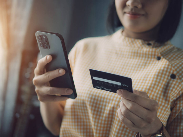 Concepto de pago en línea, Mujer una tarjeta de crédito y el uso de teléfono inteligente para las compras en línea. Mujer asiática usando smartphone comprando en línea con tarjeta de crédito. - Foto, Imagen