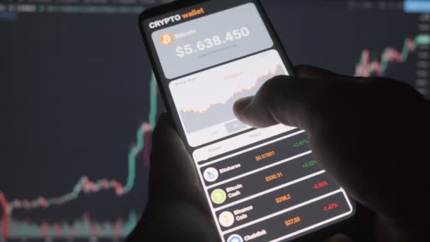  Smartfon z aplikacji mobilnej kryptowaluta portfel. Mężczyzna analizuje wykres cen bitcoinów w aplikacji mobilnej. Koncepcja handlu kryptowalutą - Materiał filmowy, wideo