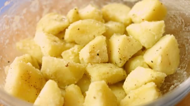 Gekochte goldene Kartoffeln, gewürzt mit Öl, Salz und schwarzem Pfeffer in einer Glasschüssel. Prozess der Zubereitung perfekter Bratkartoffeln im Ofen - Filmmaterial, Video