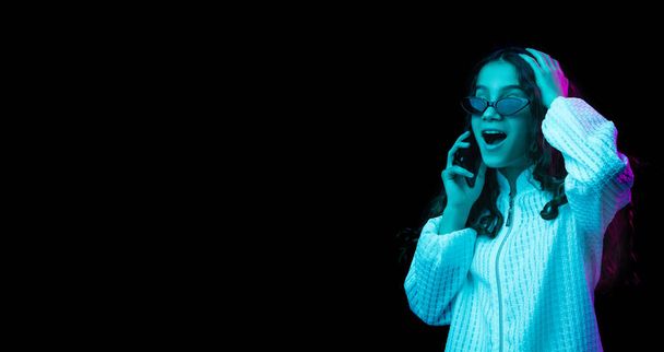 Giovane bella ragazza che parla al telefono isolato su sfondo scuro in luce al neon - Foto, immagini