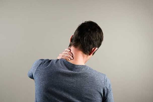 Boynu ağrıyan bir adamın arka görüntüsü. Ofiste sağlık sorunu. Yüksek kalite fotoğraf - Fotoğraf, Görsel