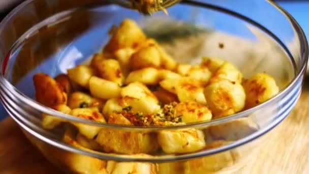 Pečené zlaté brambory kořeněné smaženým česnekem a jemně nasekanou rozmarýnem ve skleněné míse. Proces vaření perfektní pece pečené brambory - Záběry, video