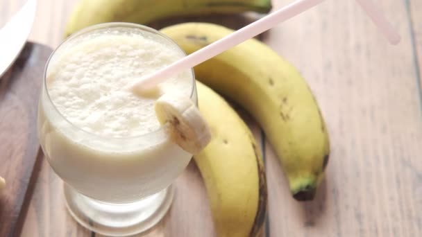  batido de leche de plátano de vidrio y plátano en la mesa por la mañana  - Imágenes, Vídeo