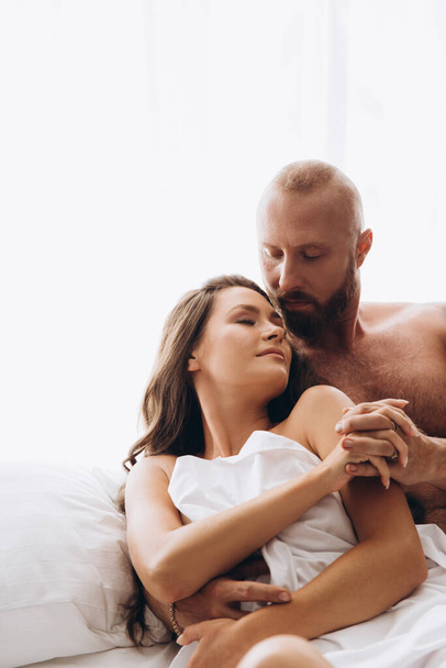 Loving couple in bed on white sheets. - Fotoğraf, Görsel