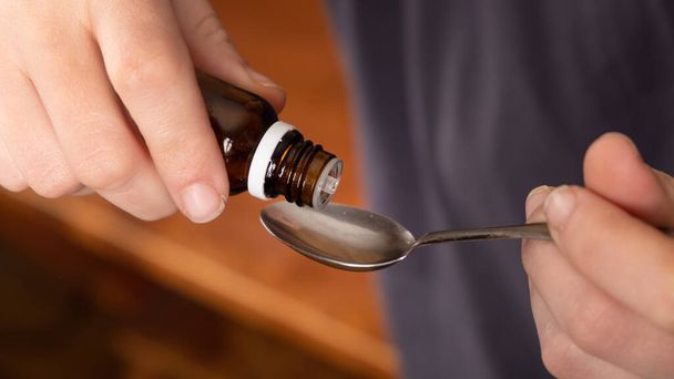 Medikamente aus einem Löffel nehmen, Hustensaft tropfen lassen - Foto, Bild