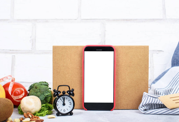 Biolebensmittel und Telefon mit weißer Attrappe, Bastelkarte mit DASH DIET-Aufschrift, kleine Uhr, gesunde Ernährungszusammensetzung. Kulinarischer Blog, Rezeptvorlage, Online-Kochkurse. - Foto, Bild