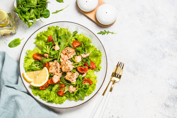 Salade verte aux poissons cuits au four à table blanche. - Photo, image