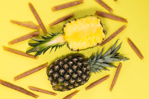fruit roll up met ananas op een gele achtergrond bovenaanzicht. Vruchtpastille. Veganistisch zelfgemaakte zoetigheden. - Foto, afbeelding