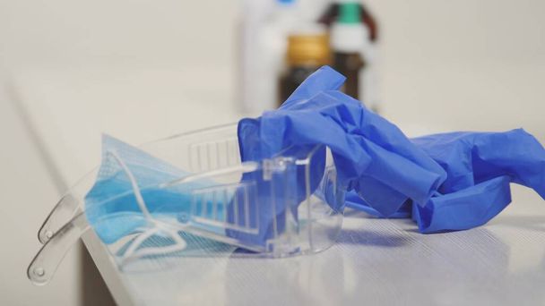 Masque protecteur et gants bleus sur la table médicale de l'hôpital central, examen du patient par le gynécologue, covide-19, pandémie de coronavirus, traitement de la santé par un professionnel - Photo, image