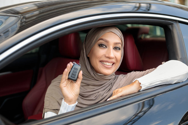 Senhora muçulmana mostrando chaves de automóvel, sentado no assento dos motoristas - Foto, Imagem