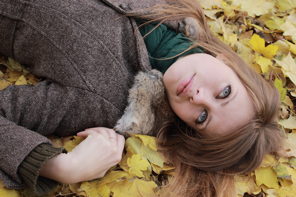 Girl in the sunny autumn day lying on maple leaves - Фото, изображение