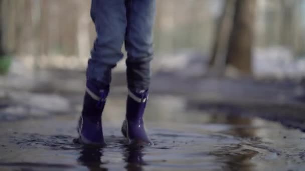 happy boy rubber boots have fun playing in a puddle, on road - 映像、動画