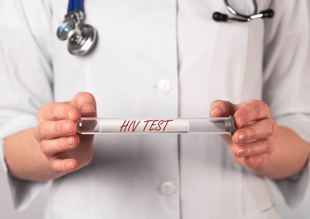 HIV test inscription on glass test tube in doctor hands. - Фото, зображення