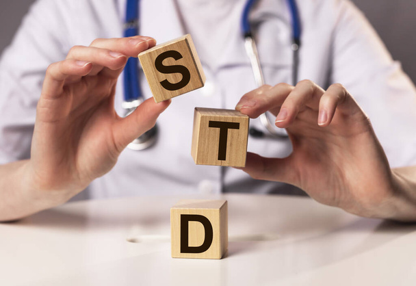 STD acronym inscription on wooden cubes in doctor hands. - Фото, изображение